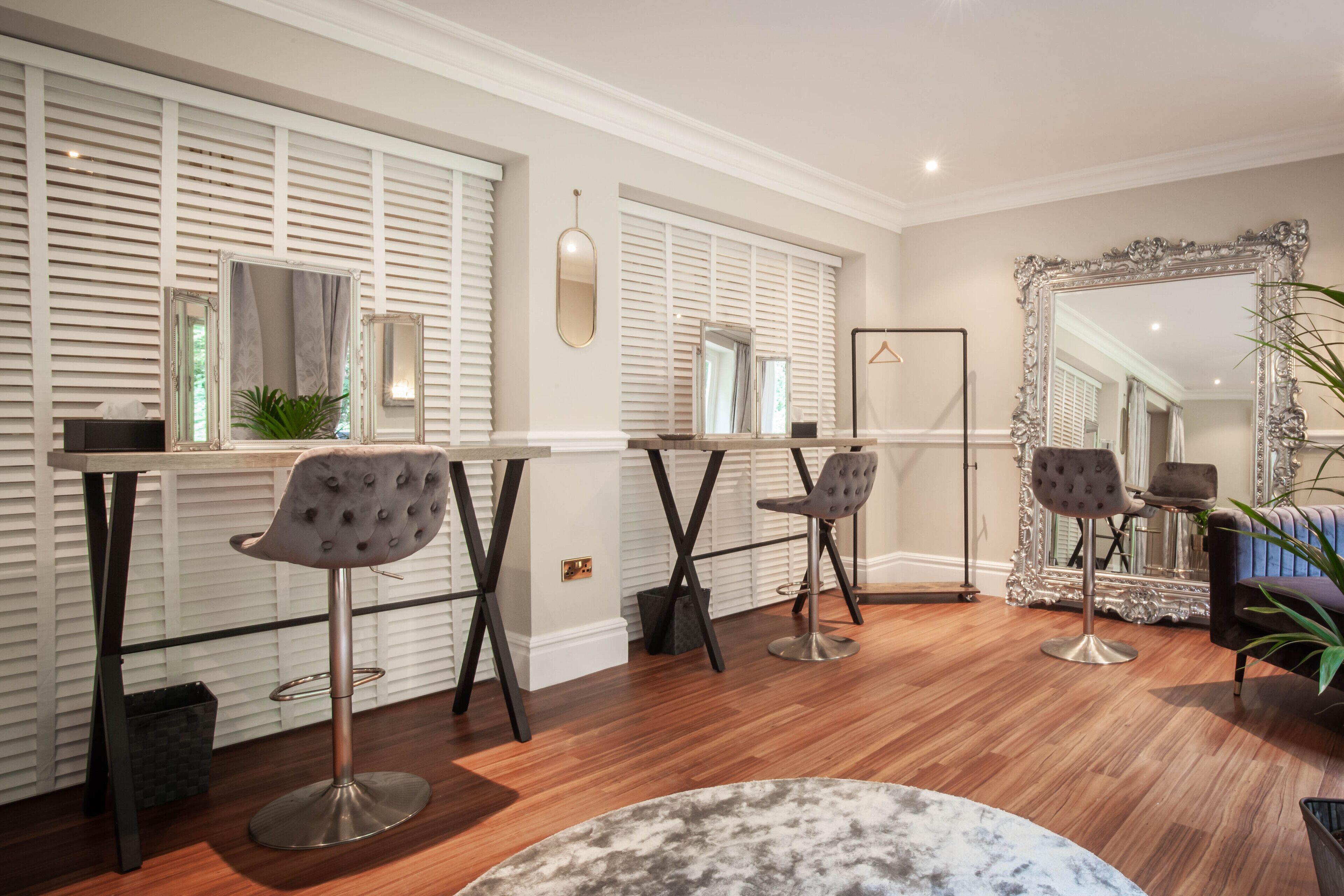 A modern interior with a bar area, two bar stools, a round table, and a large mirror.
