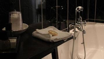 A bathroom with a white bathtub, a towel, and a soap dish on a black countertop.
