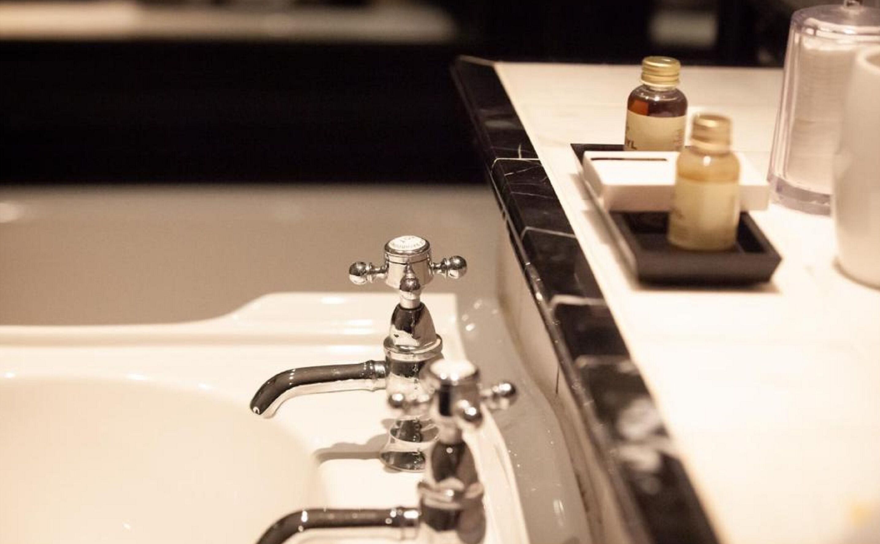 A bathroom sink with a chrome faucet and a soap dispenser on the countertop.