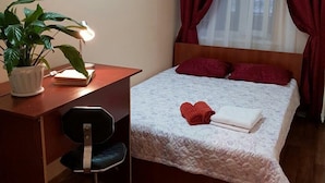 A bedroom with a bed, a desk, a chair, and a potted plant. - FM Hostel Almaty (Almaty)