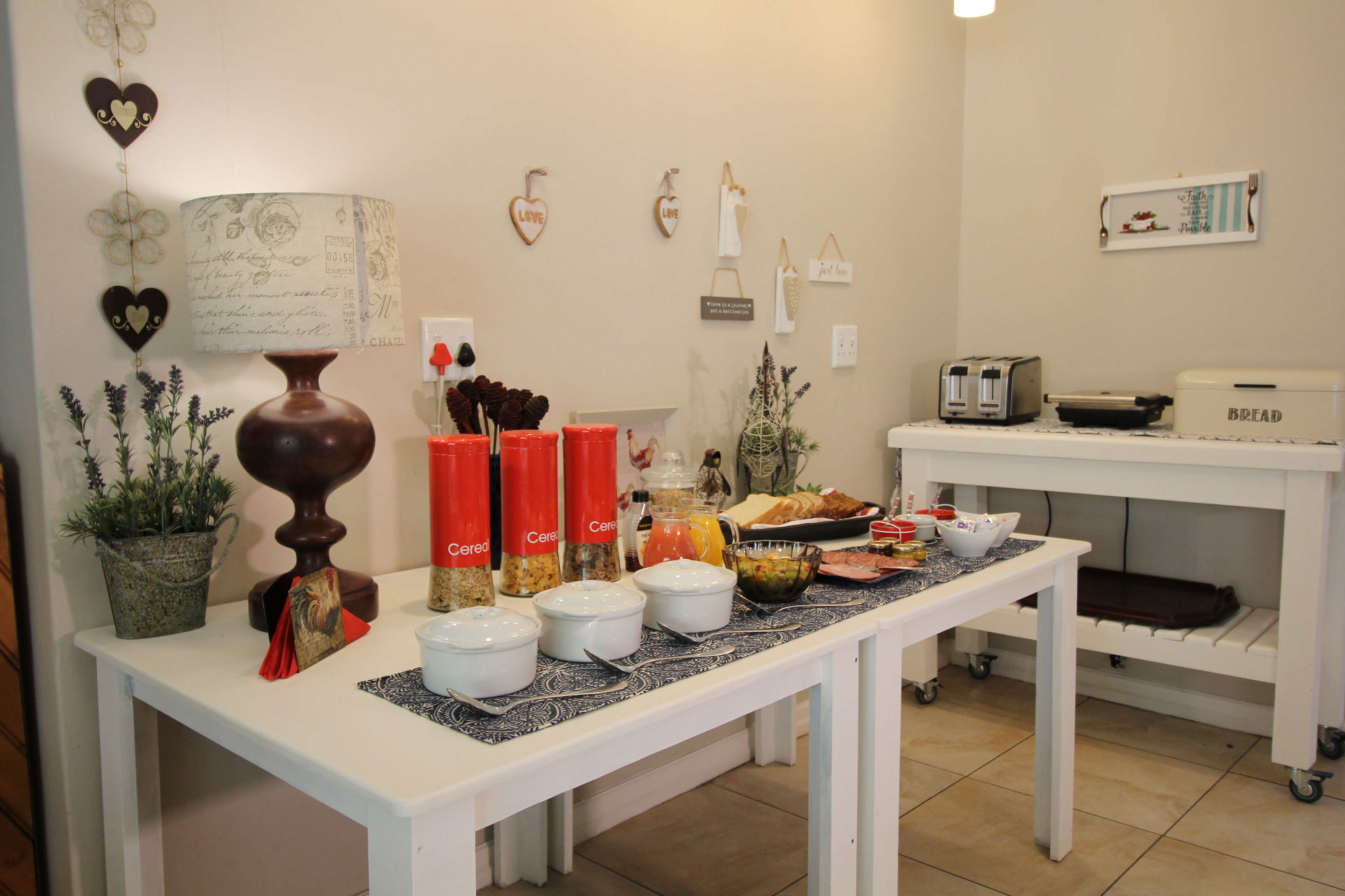 A breakfast buffet setup with various food items and containers on a table, surrounded by decorative wall elements.