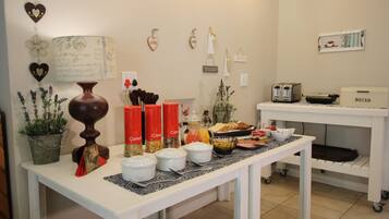 A breakfast buffet setup with various food items and containers on a table, surrounded by decorative wall elements.
