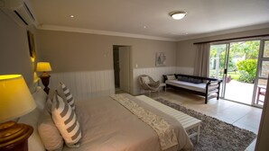 Een slaapkamer met een bed, bedlampen, een bankje en uitzicht op het omliggende landschap.