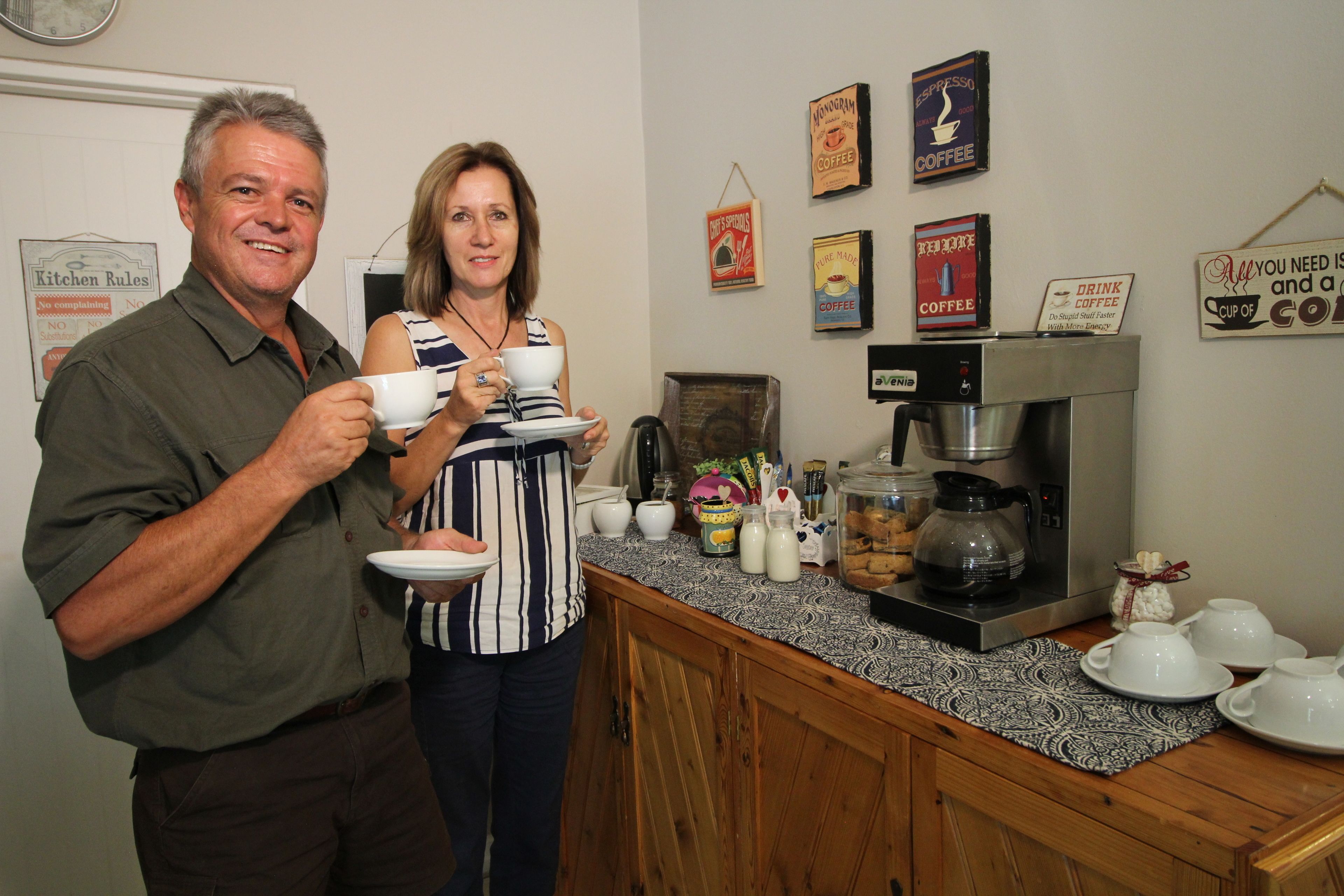 Una cuina amb armaris de fusta, una màquina de cafè i diversos objectes relacionats amb el cafè damunt el taulell.