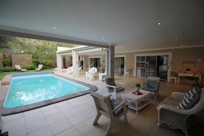 Un espace aménagé au bord de la piscine, comprenant une piscine, des chaises longues et un patio couvert.