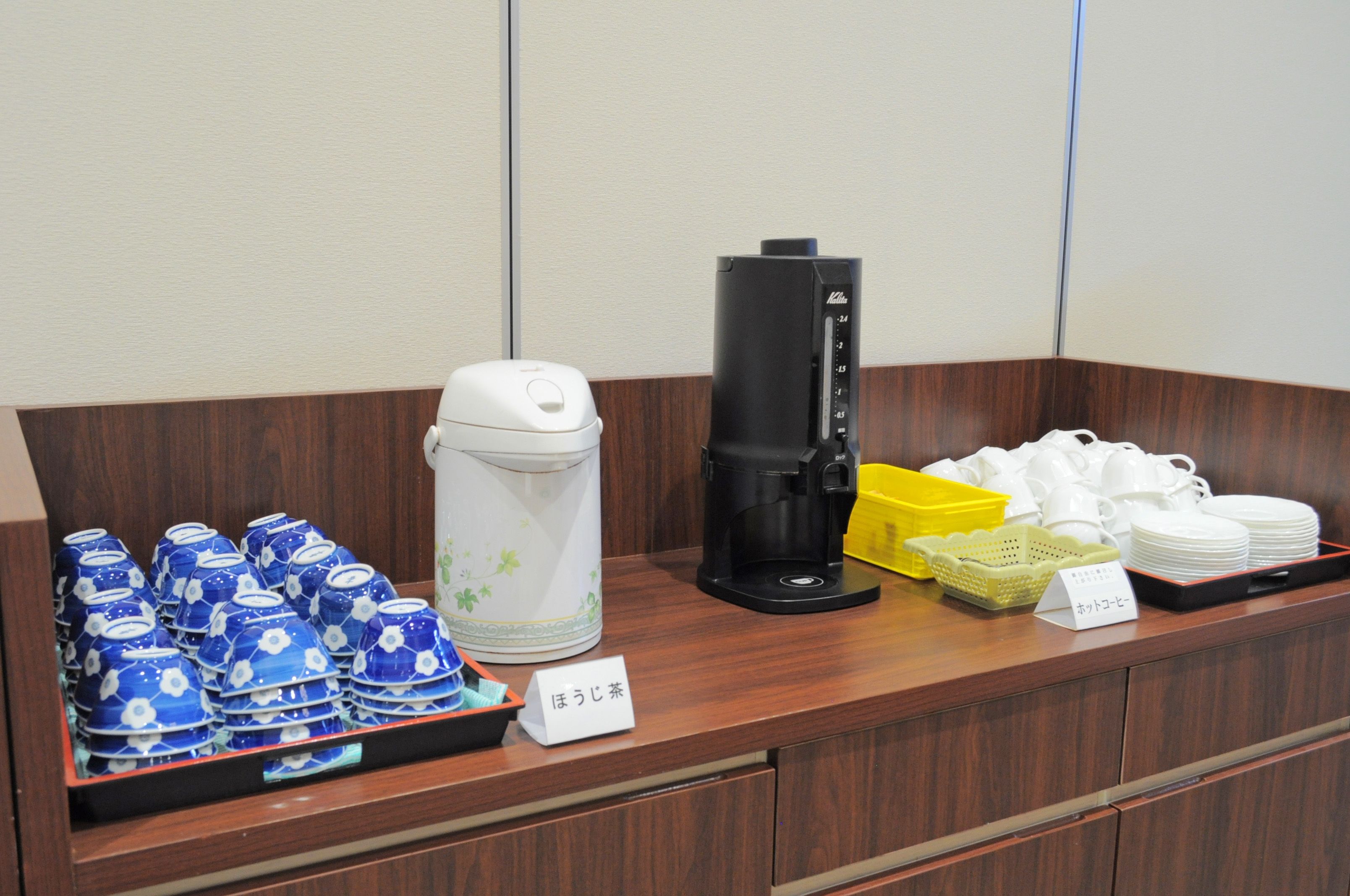 Ein Buffet mit blauen und weißen Keramikgeschirr, einer Kaffeemaschine und einem Schild, das einen Tee-Service anzeigt.