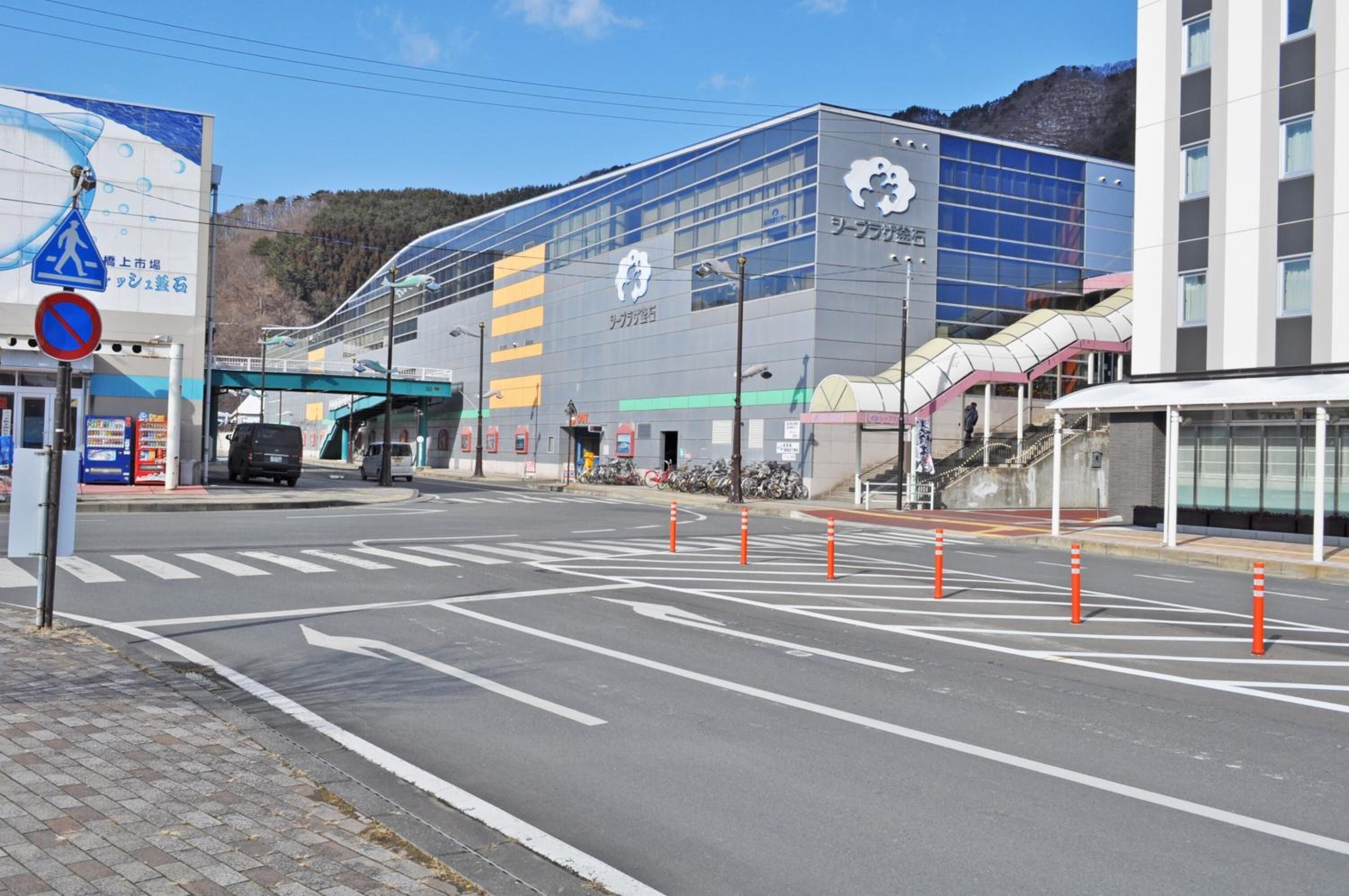 A modern building with a glass facade, a pedestrian crossing, and a no parking sign.
