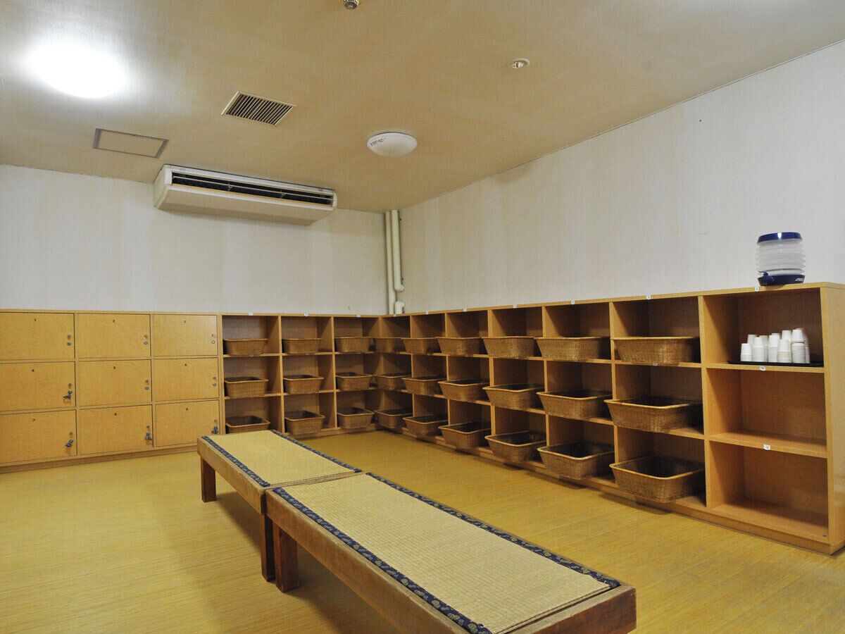 A room with a tatami mat, wooden shelves with baskets, and a water dispenser.