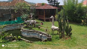 A garden with a pond, cacti, and animal sculptures. - Villa Pribadi Beunying 35 pax (Cipanas)