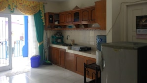 A kitchen with wooden cabinets, a refrigerator, and a tiled backsplash. - Villa Abdi Cipanas with Swimming Pool (Cipanas)