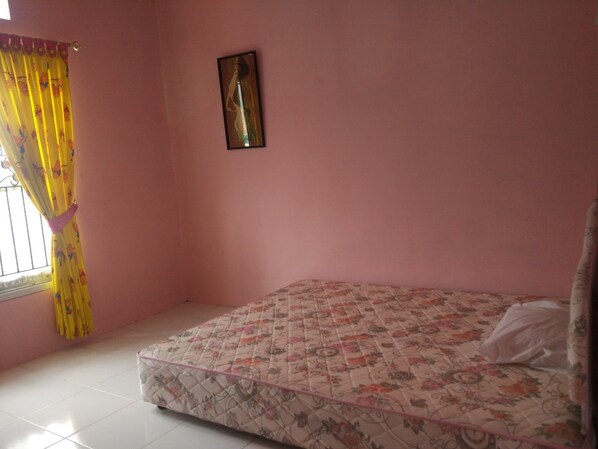 A room with a bed, a window with yellow curtains, and a framed picture on the wall.