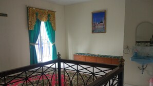 A room with a red carpet, a wooden cabinet, a blue sink, and a painting of a mosque on the wall. - Villa Abdi Cipanas with Swimming Pool (Cipanas)