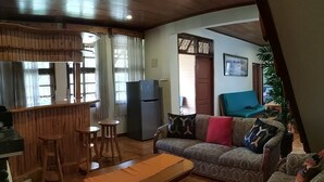 A living room with a wooden bar, a sofa, and a bench. - Villa Bumblebee 2 – Little Venice Puncak (Cipanas)