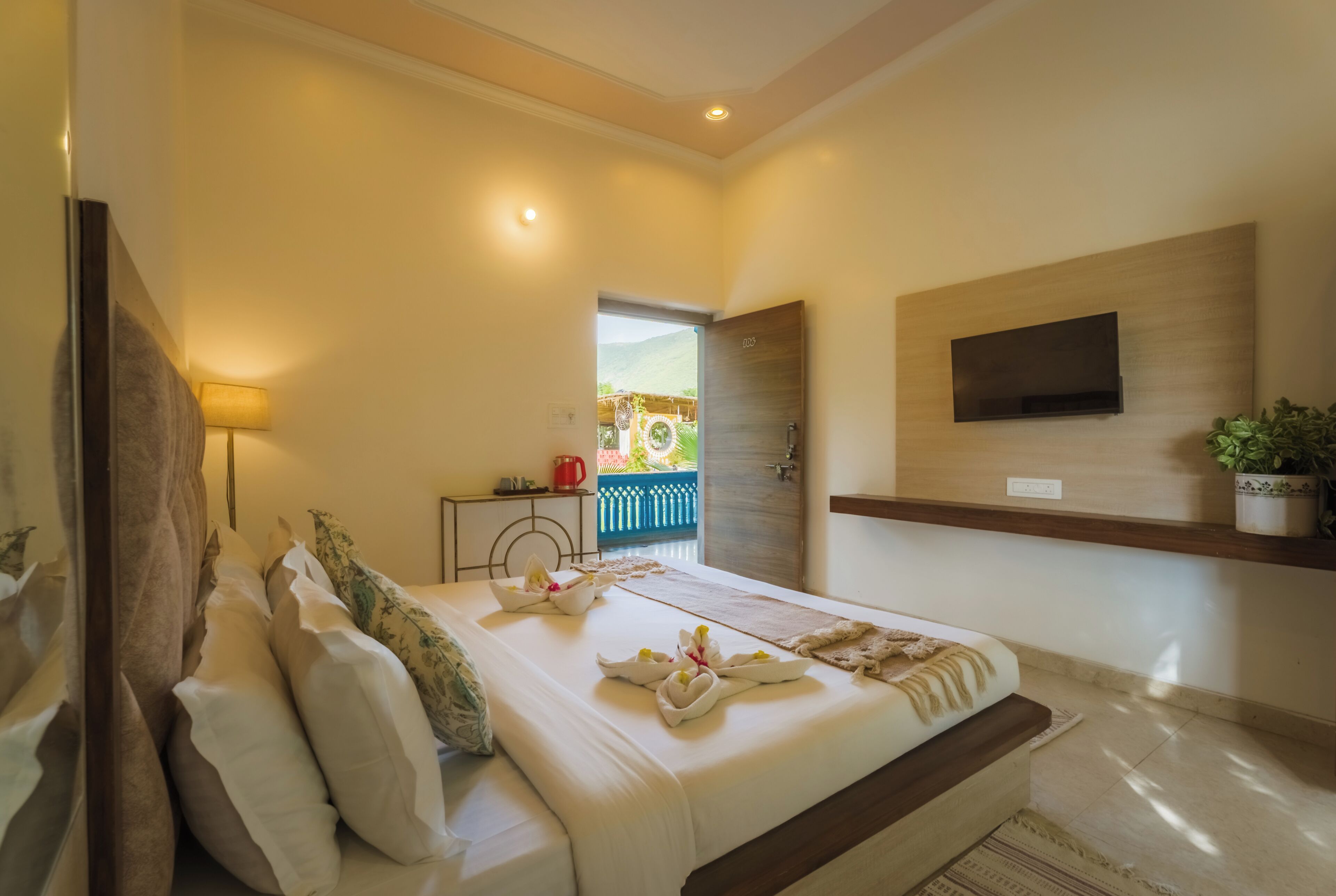 A hotel room with a bed, a TV mounted on the wall, and a view of the outside.