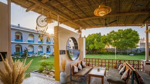 A covered outdoor seating area with a patterned floor, a sofa, and a table. - Moustache Pushkar - Hostel (Pushkar)