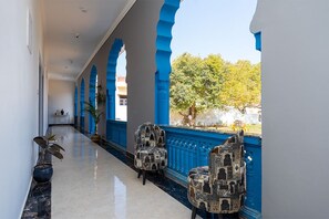 Un pasillo con arcos azules, plantas en macetas y sillas con estampado.