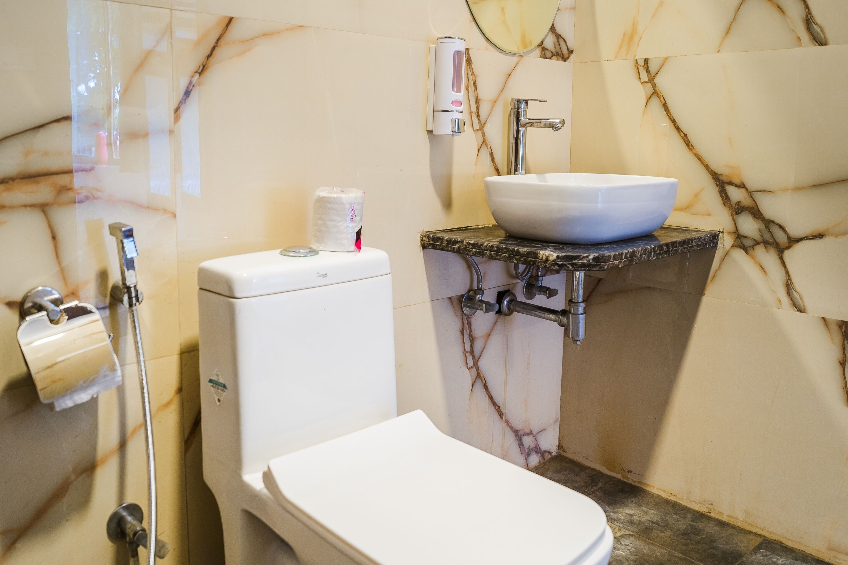 A bathroom with a toilet, a sink, and a paper towel dispenser.
