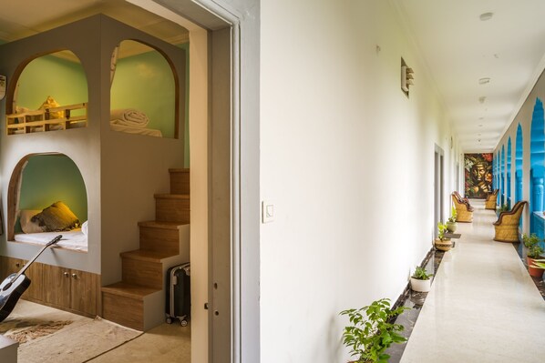 A hallway with a staircase, a guitar, and a suitcase.