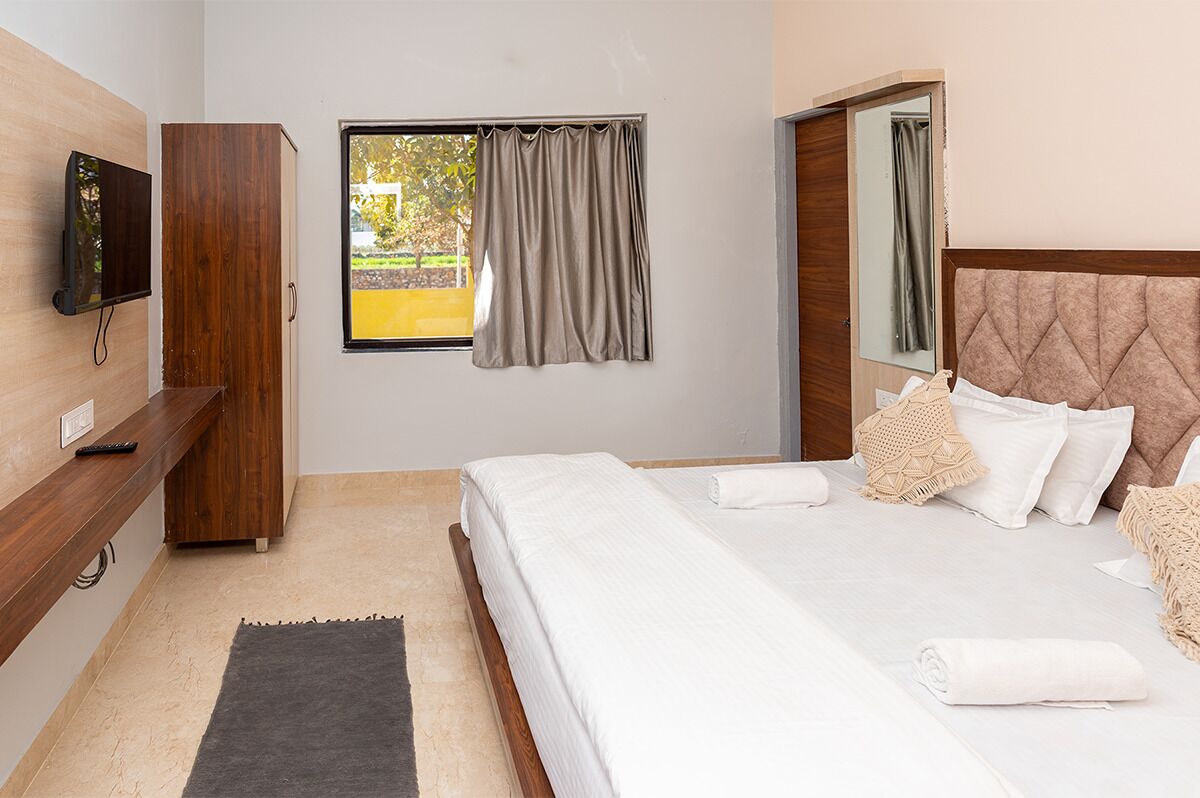 Ein Schlafzimmer mit einem Bett, einem Fernseher, einem Kleiderschrank und einem Fenster mit Vorhängen.