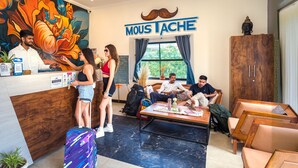 A hotel lobby with a reception desk, a mural, a large window, and seating areas. - Moustache Pushkar - Hostel (Pushkar)