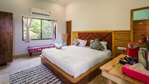 A neatly arranged bedroom with a large bed, a bedside table, a bench, and a window with curtains. - Moustache Pushkar - Hostel (Pushkar)