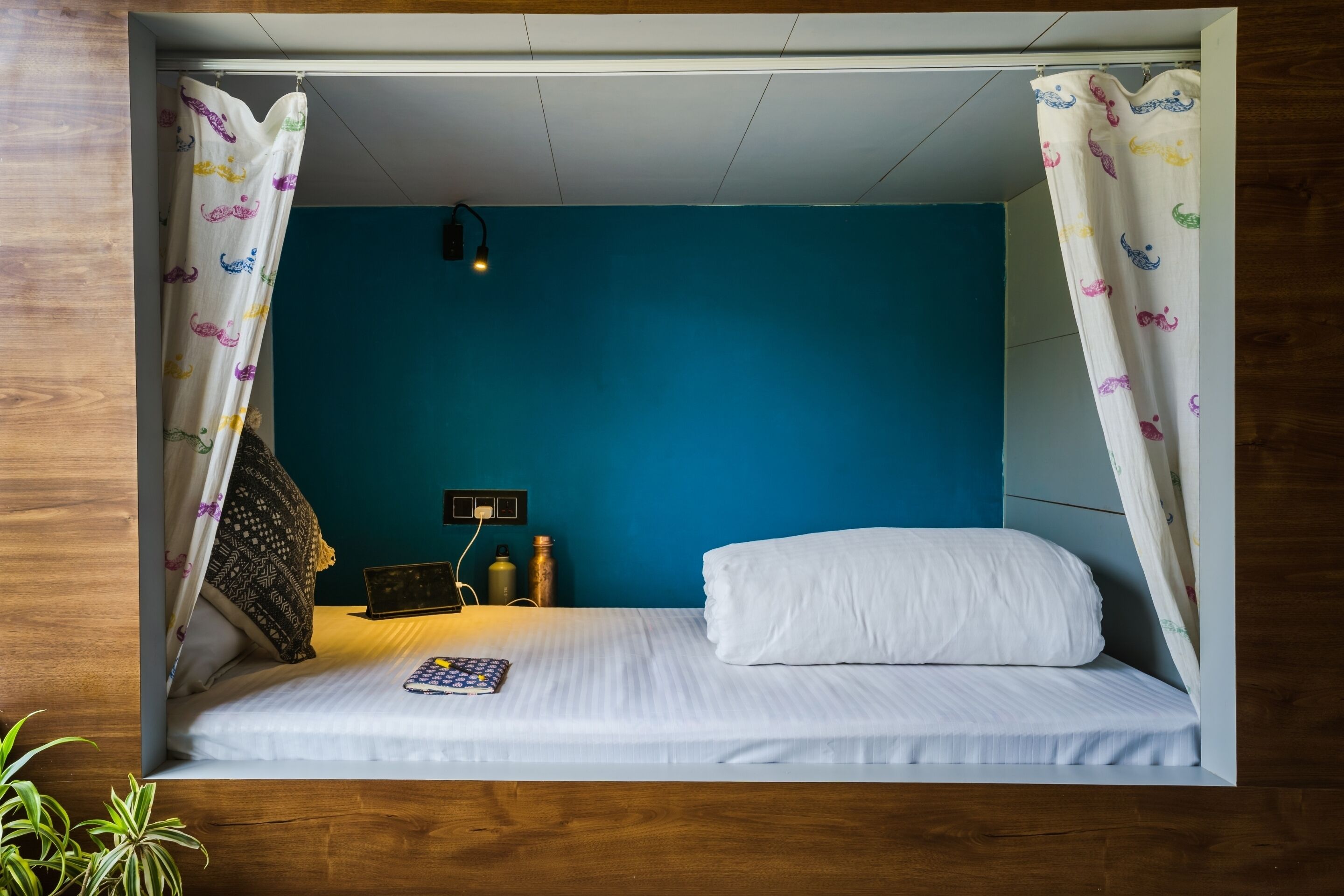 A bed with white linens, a bedside lamp, and a small table with a book.