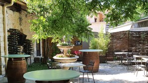 An outdoor patio area with rustic wooden barrels used as tables, surrounded by stone flooring. - Le Bistrot Vinaigrette (Prades-le-Lez)