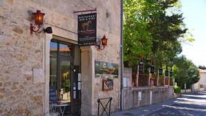 A stone building with a restaurant/bar sign, outdoor seating, and a street view. - Le Bistrot Vinaigrette (Prades-le-Lez)