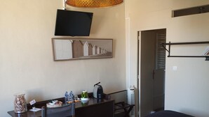 A hotel room with a bed, a desk with a chair, a television mounted on the wall, and a large window. - Le Bistrot Vinaigrette (Prades-le-Lez)