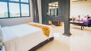 A hotel room with a large bed, a TV, a sofa, and a view of the outdoors. - Panorama Summit Hotel (Davao)