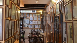 A hallway with framed pictures on the walls, a dining area with chairs, and a staircase leading to another floor. - Hostal Santa Agueda (Tarazona)