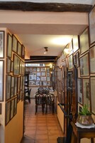 Un pasillo con cuadros en las paredes, una zona de comedor con sillas y una escalera que sube a otro piso.