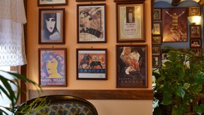 A wall with vintage movie posters, a patterned armchair, and a potted plant. - Hostal Santa Agueda (Tarazona)