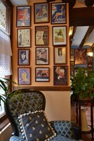 Una pared con carteles de películas antiguos, un sillón estampado y una planta en maceta.