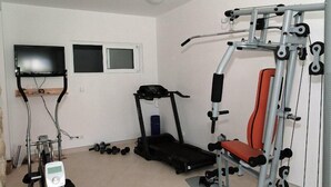 A home gym with a treadmill, elliptical, and weight bench. - Villa Marina Betina (Tisno)