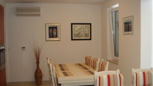 A dining area with a table and chairs, framed artwork on the wall, and a window. - Villa Marina Betina (Tisno)