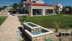 A modern house with a stone facade, large windows, and a swimming pool in the front yard. - Villa Marina Betina (Tisno)