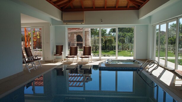An indoor swimming pool with a view of a garden and a stone archway. - Villa Marina Betina (Tisno)