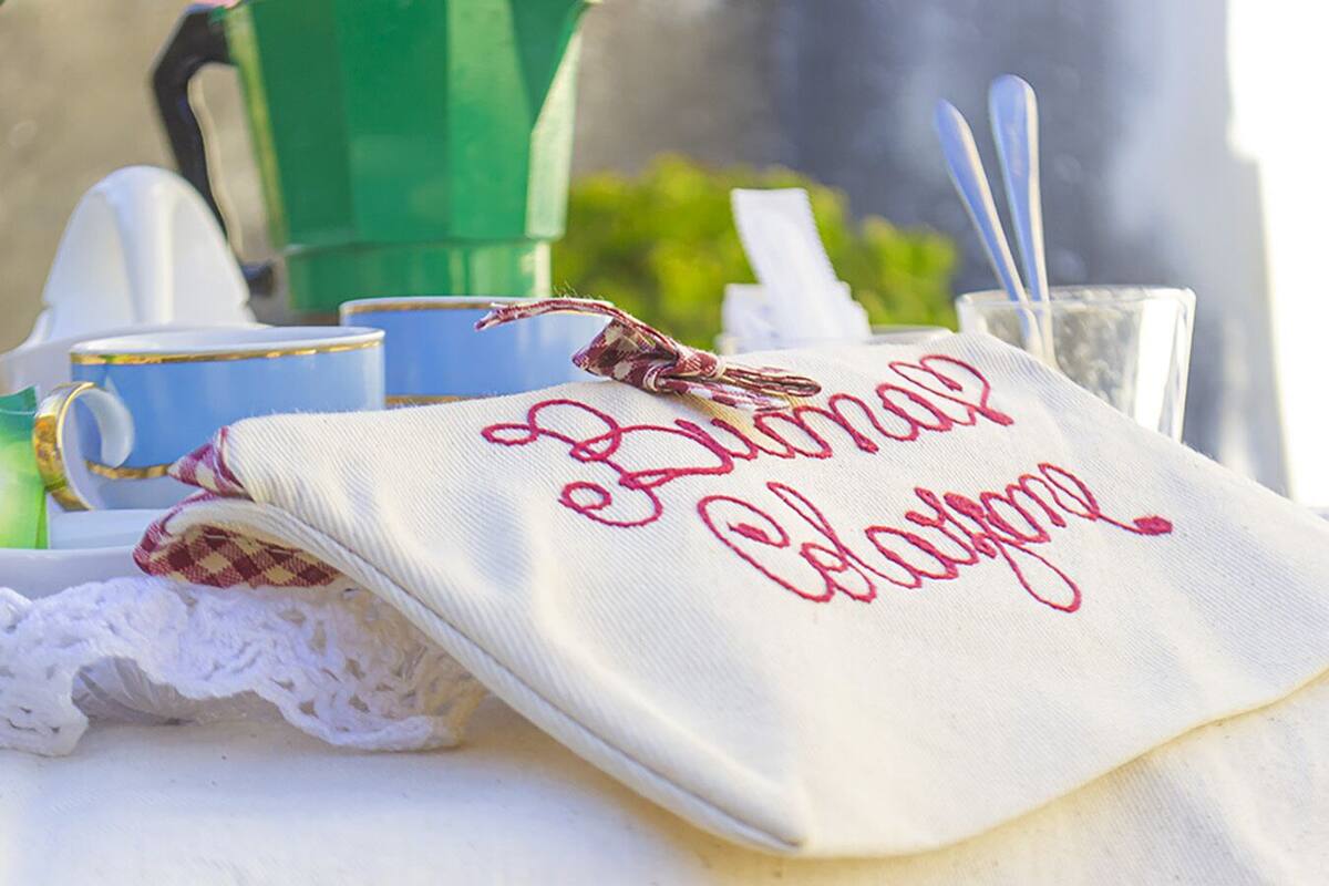 A table with a white cloth bag embroidered with "Blimar Clawgr."