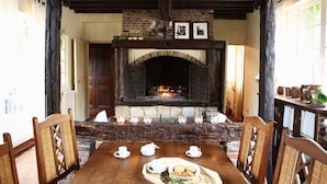 A rustic dining area with a brick fireplace, wooden chairs, and a table set for tea. - Le Logis De Gerberoy (Gerberoy)