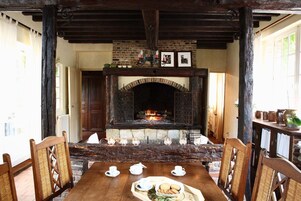 Un comedor rústico con chimenea de ladrillo, sillas de madera y una mesa dispuesta para el té.