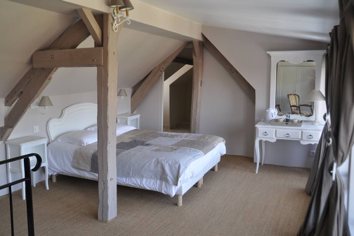 A bedroom with a bed, a dresser, a mirror, and a chair.