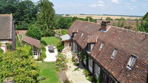 A traditional half-timbered house with a garden pathway, surrounded by greenery and a rural landscape. - Le Logis De Gerberoy (Gerberoy)