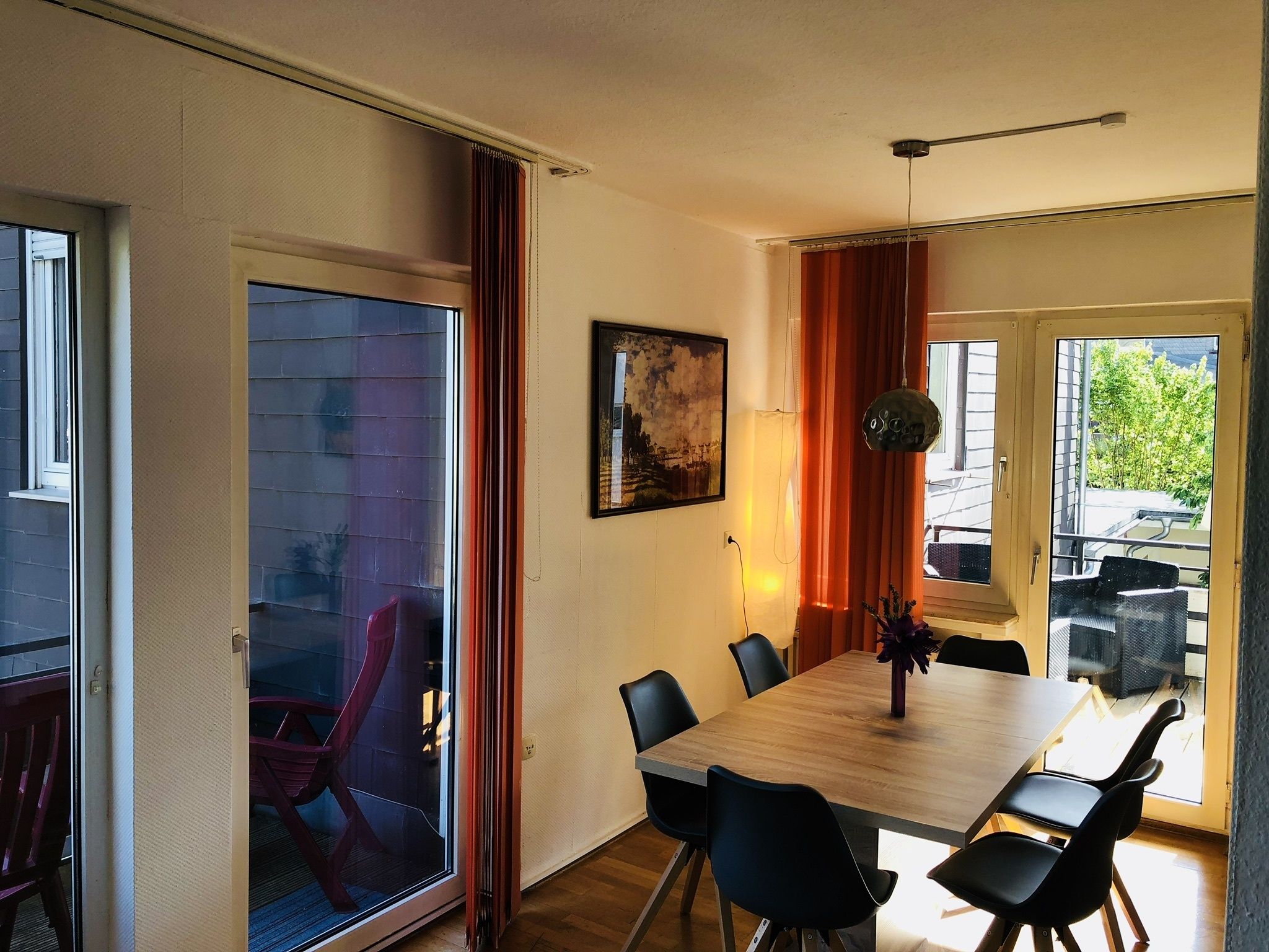 A dining area with a wooden table, black chairs, and a glass partition.