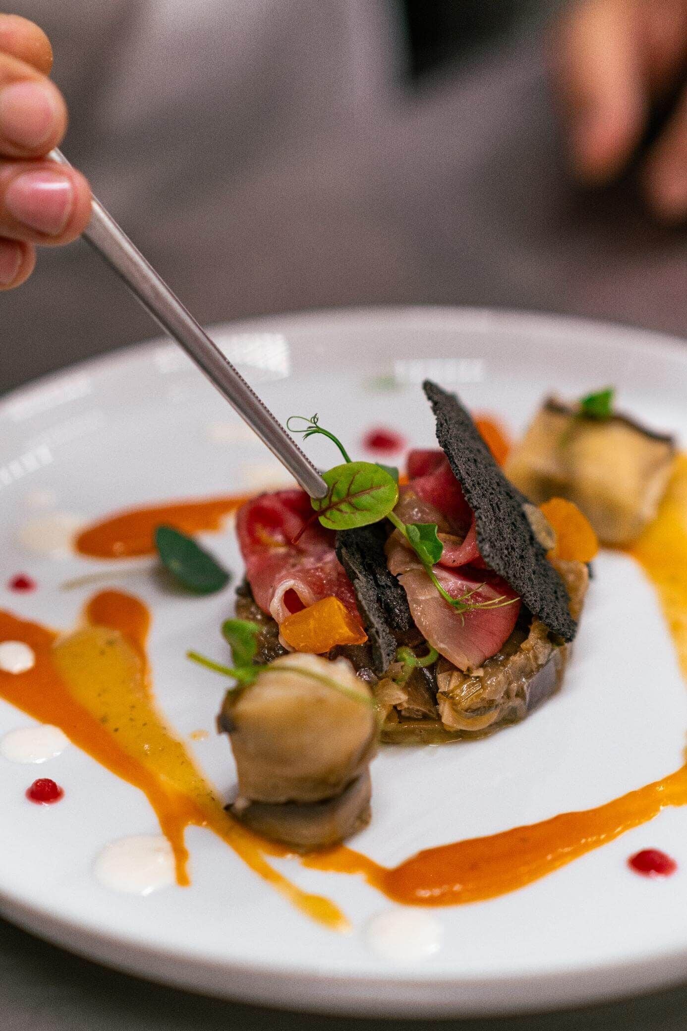 A close-up of a gourmet dish with a fork, featuring various ingredients and sauces.