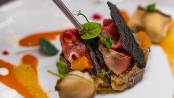 A close-up of a gourmet dish with a fork, featuring various ingredients and sauces.