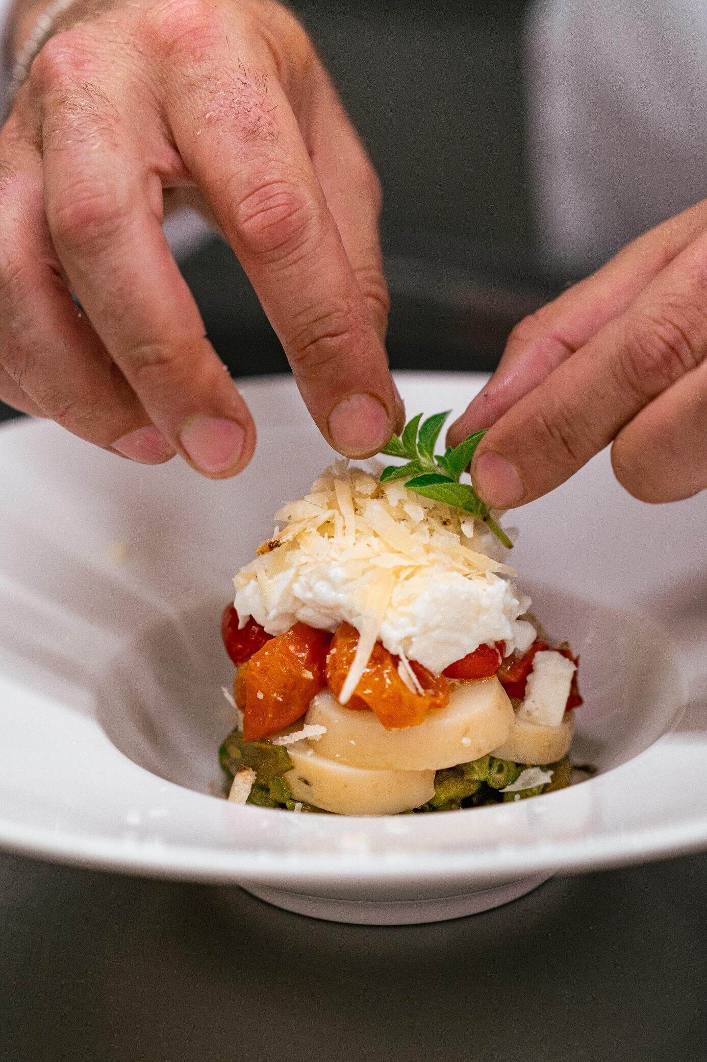 Una persona colocando una hoja en un plato con comida.