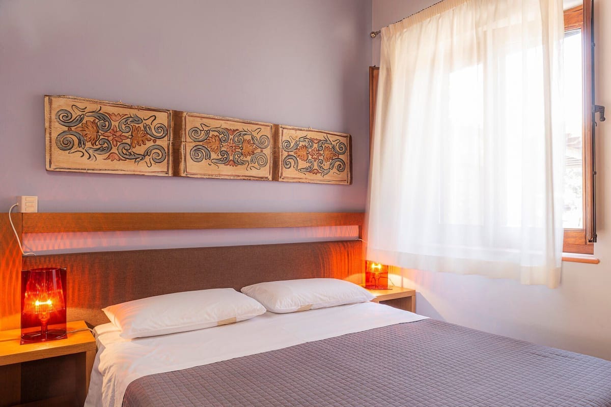 A neatly made bed with a quilted cover, two bedside lamps, and a headboard.