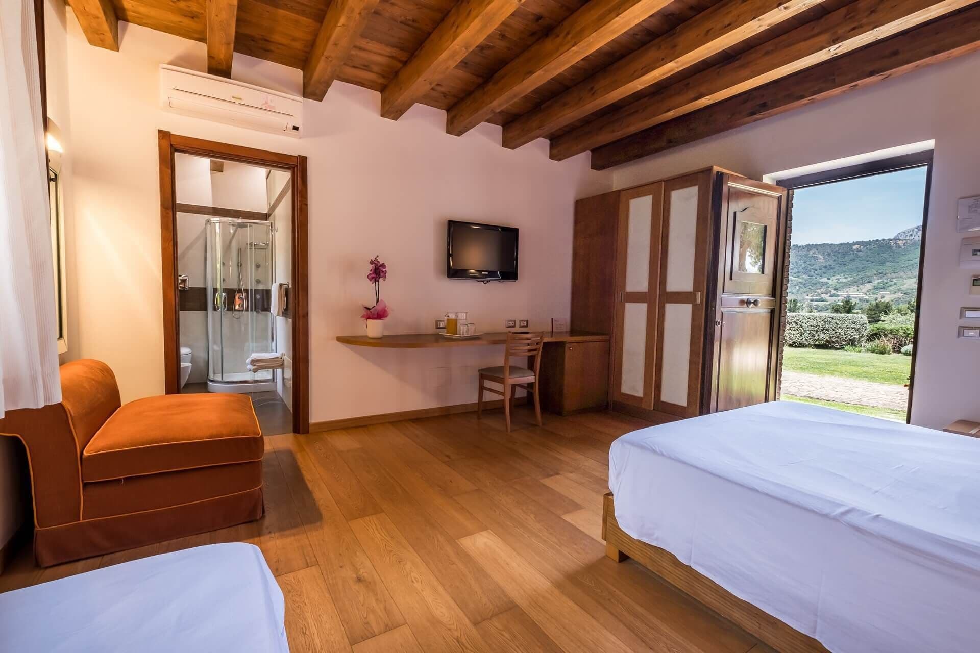 Een slaapkamer met twee bedden, een bureau, een stoel, een televisie en een douche.