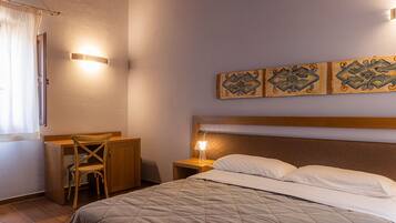 A bedroom with a bed, a desk, and a chair. There are wall-mounted lights and a decorative panel above the bed.